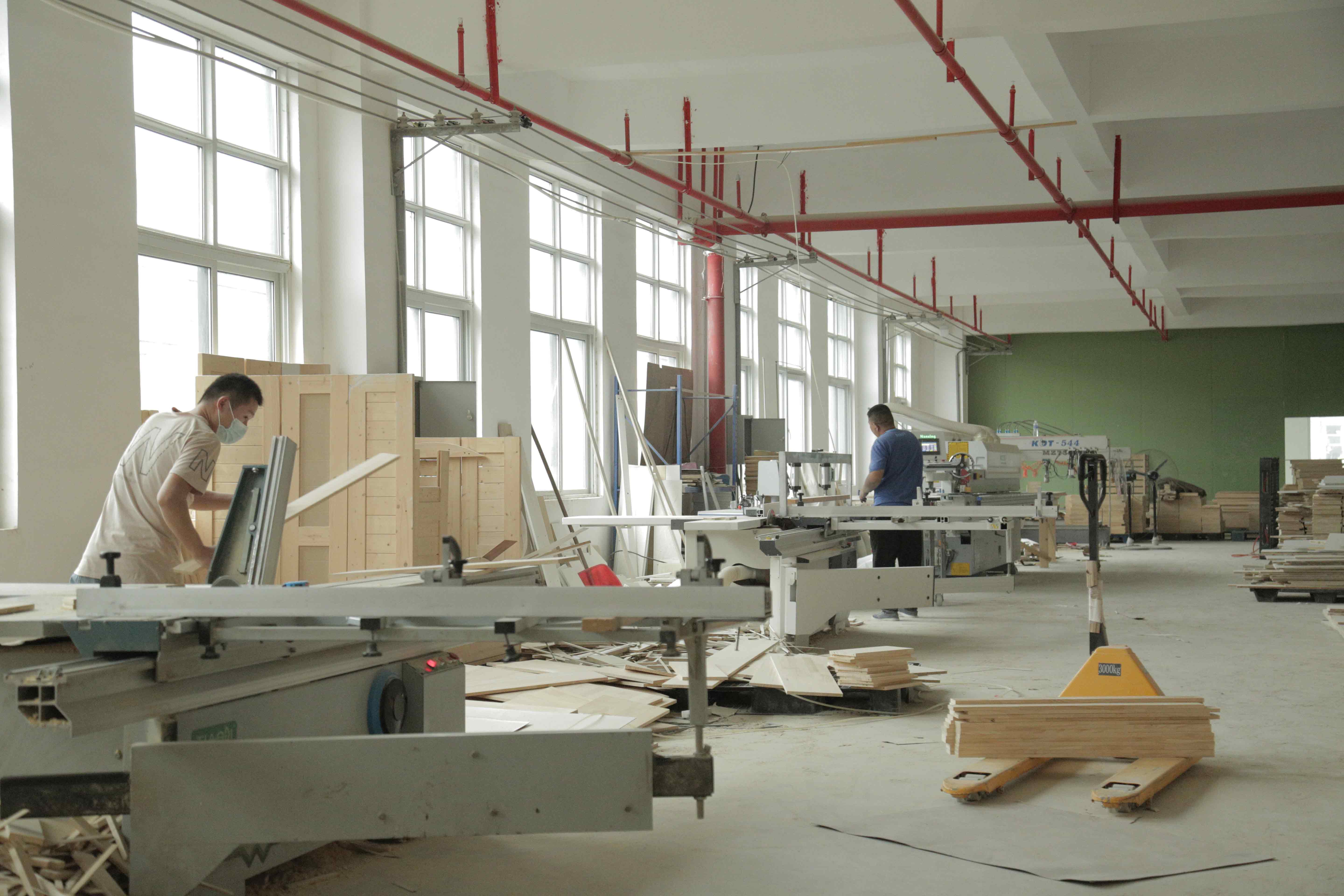 MJK Furniture factory floor in Shaji, Xuzhou — natural light through workshop windows, panel saws and multi-row boring machines in operation