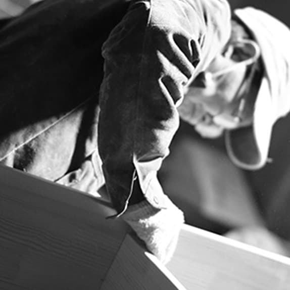 Gloved hands resting on a raw wood panel