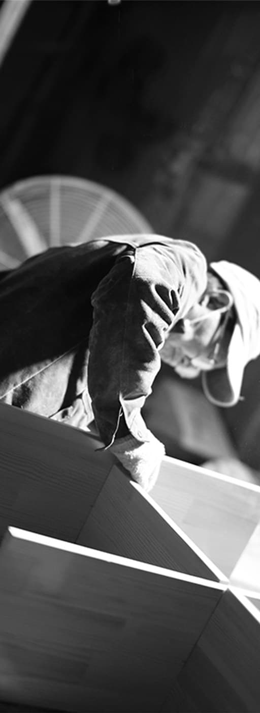 Gloved hands resting on a raw wood panel